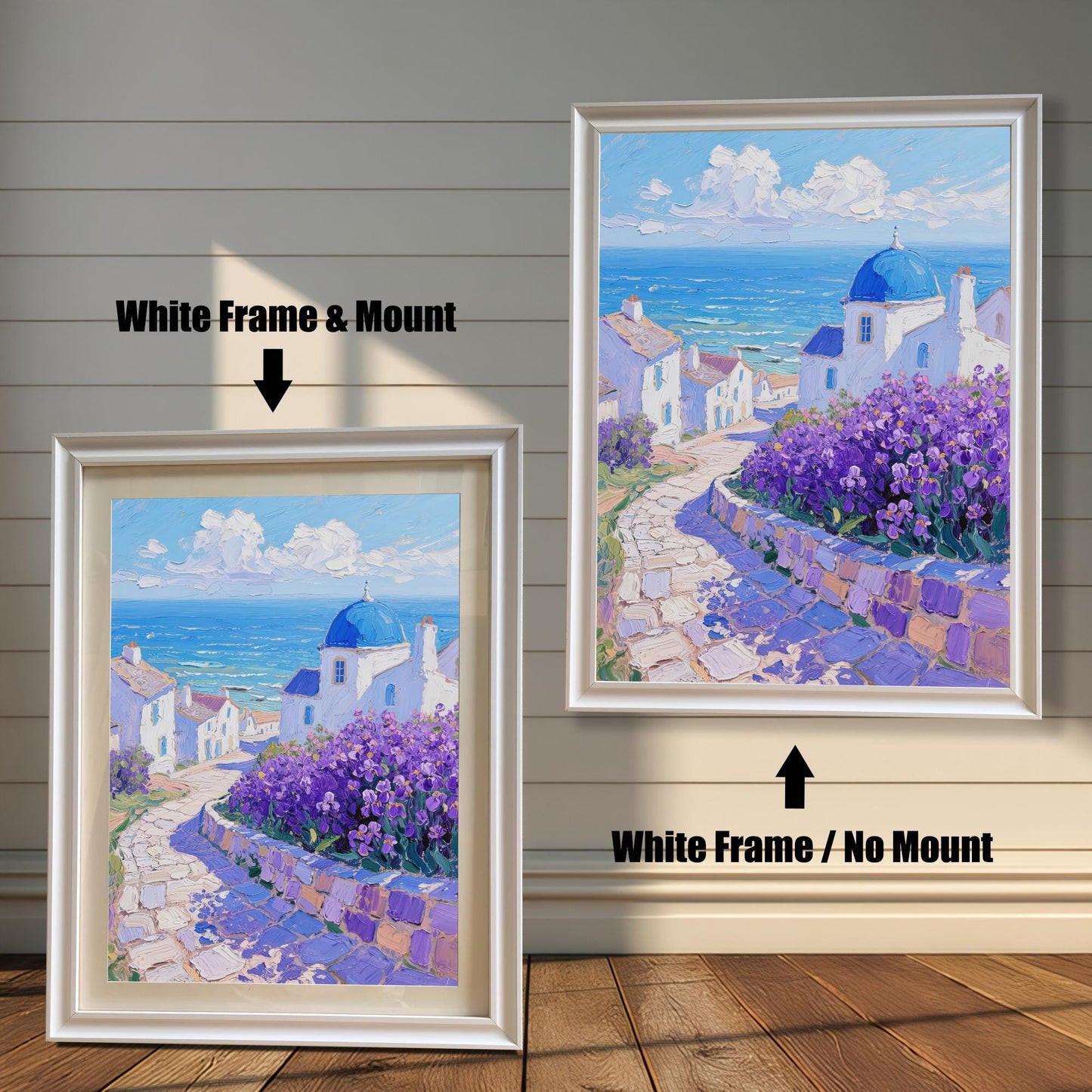 A painting of a Greek seaside village is shown in two white frames against a wood wall. One has a mount, and the other doesn't, demonstrating the framing options.