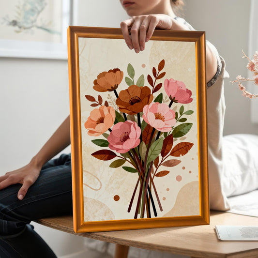 A person holding a framed floral art print in an orange frame. The print is angled towards the camera, showing a close-up of the artwork.