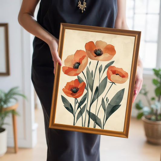 A person in a black dress holds up a framed art print of five orange poppies with a gold frame in a room with a potted plant and window.