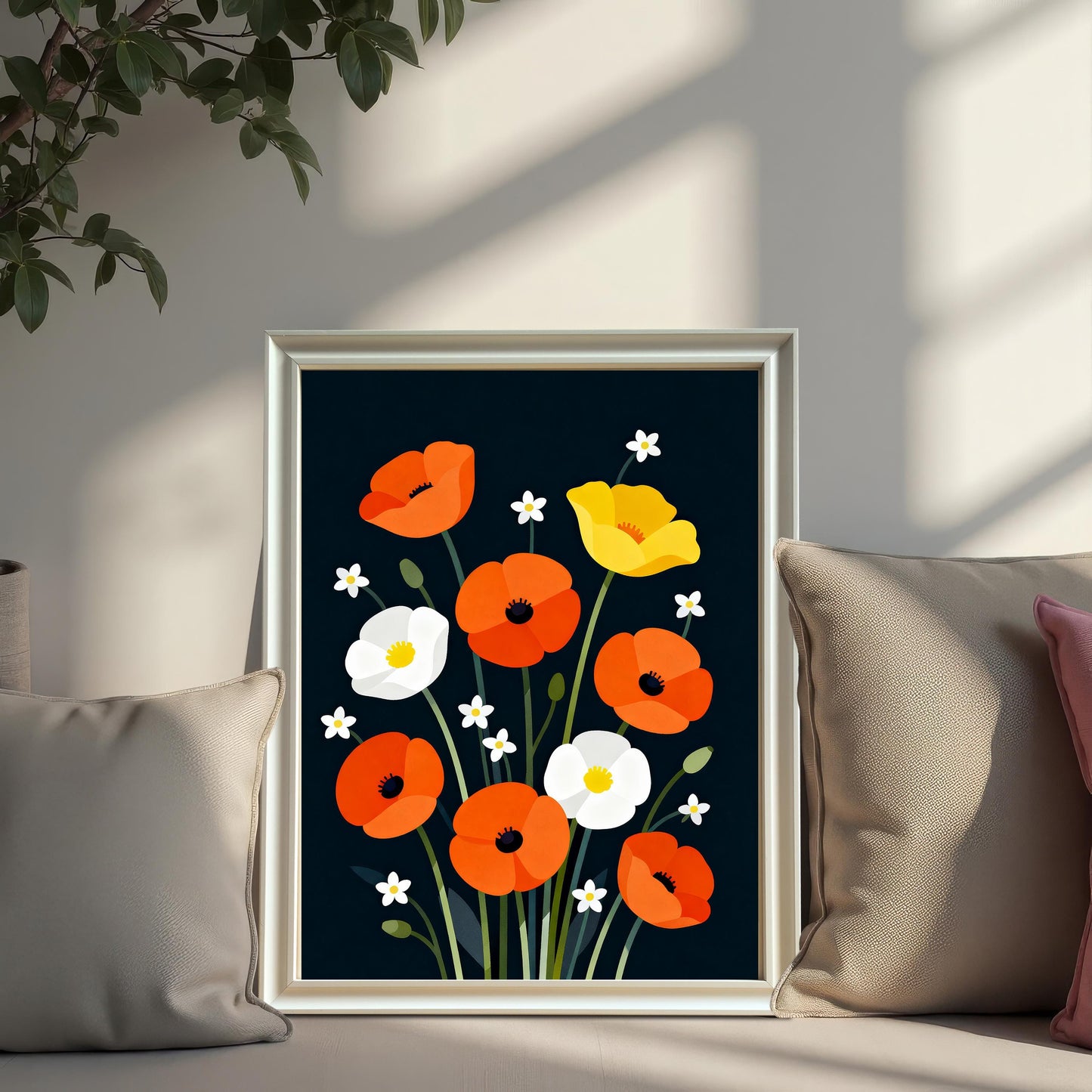 A framed print of vibrant, stylized orange, white, and yellow poppies against a dark background. The print is set in a white or silver frame and is leaning on a couch, resting between two large, neutral-toned throw pillows.