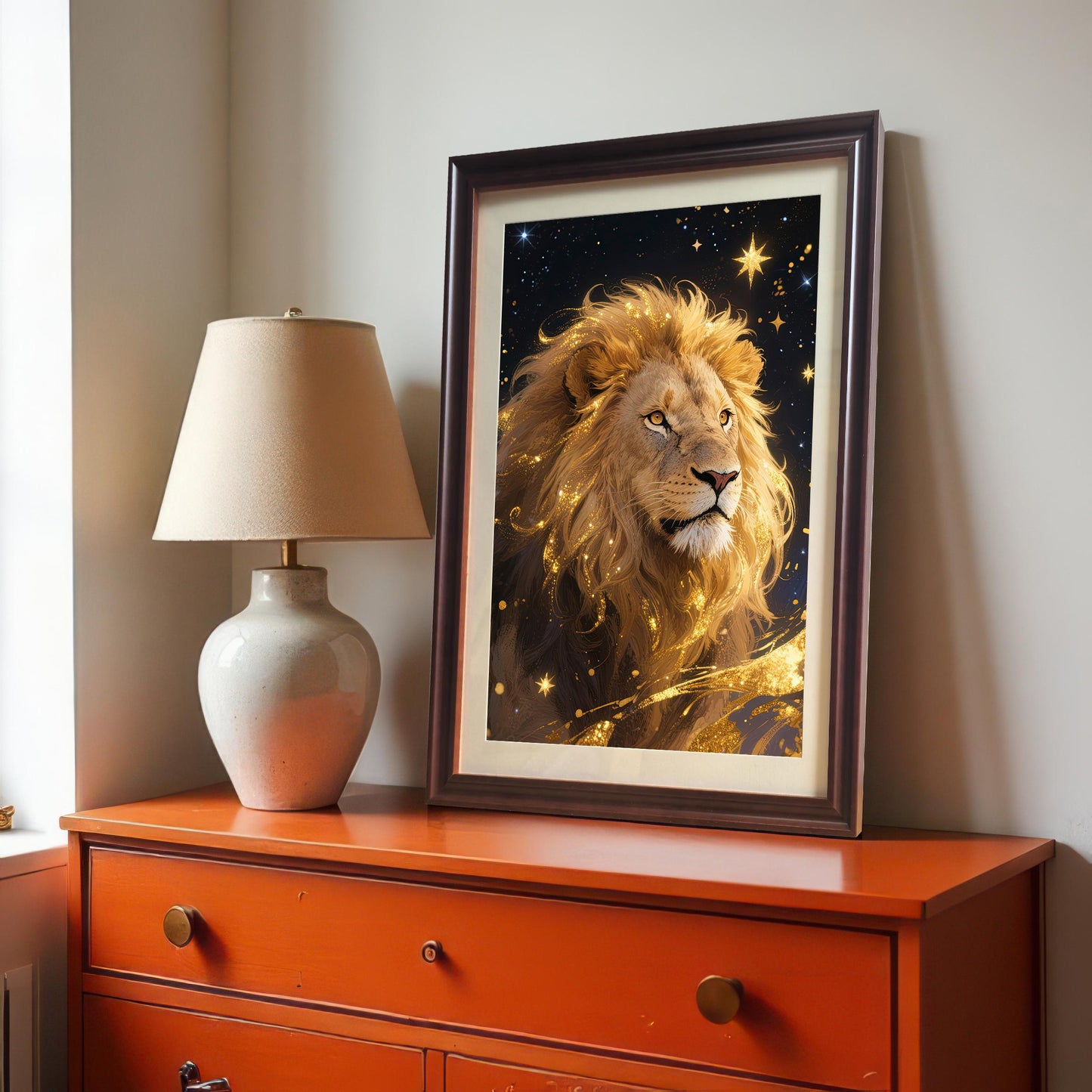 A coffee-framed art print of the majestic, golden lion portrait, sitting on an orange dresser next to a white lamp.