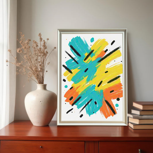 A modern, framed abstract art print featuring energetic brushstrokes in teal, yellow, and orange with black accents. The print is in a white/silver frame and displayed on a wooden dresser next to a vase of dried flowers and a stack of books.