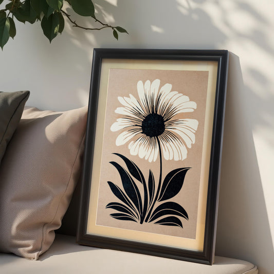 Close-up lifestyle photo of the minimalist flower art print in a Black wood frame with a mat/mount, leaning against a neutral wall with two beige pillows nearby, highlighting the black and white design on a taupe background.
