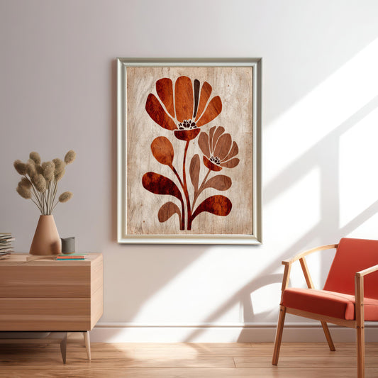 Vertical framed art print of two stylized, modern, rust-orange and brown flowers on a light, distressed wood-texture background, hanging on a white wall above a wooden side table with a vase and next to an orange chair. (This image shows the art in a lifestyle setting, emphasizing the overall look.)