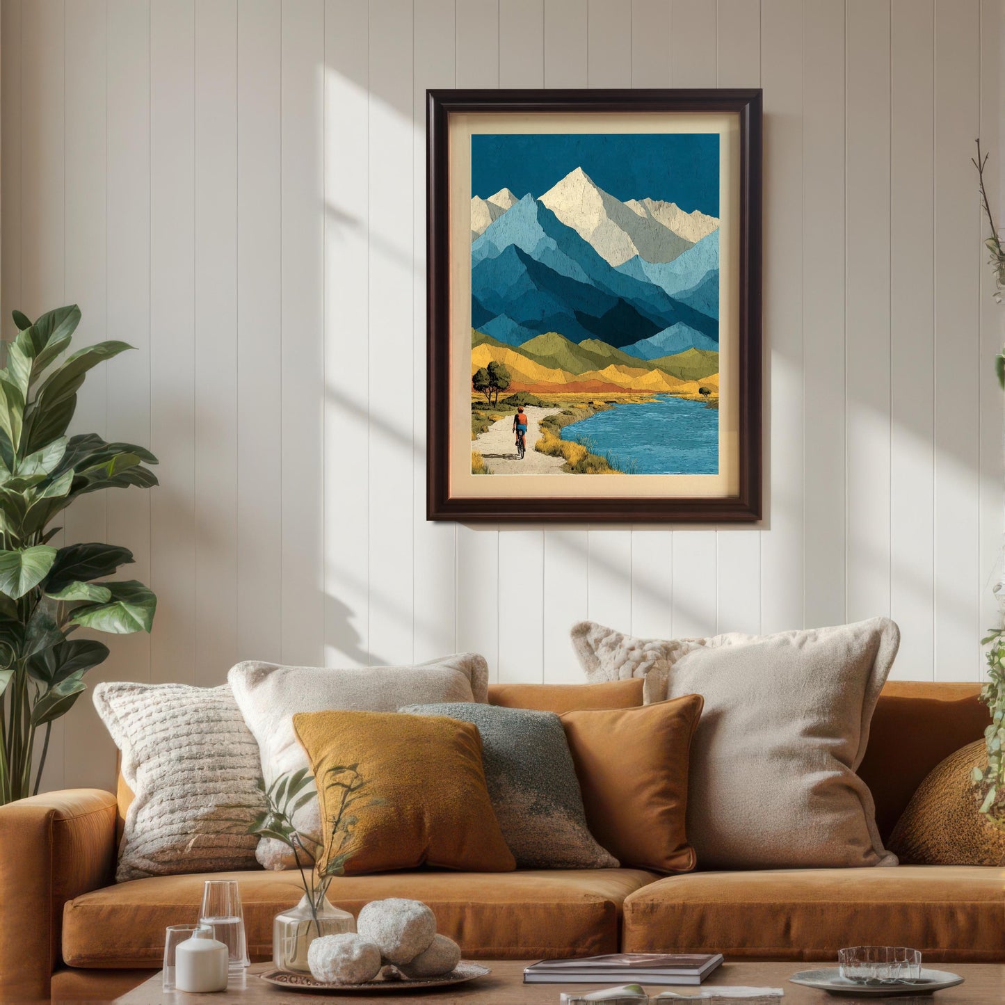 A dark brown "Coffee" wood-framed art print with a cream mat, hung on a white wood-slat wall above a cozy orange sectional sofa with various decorative pillows.