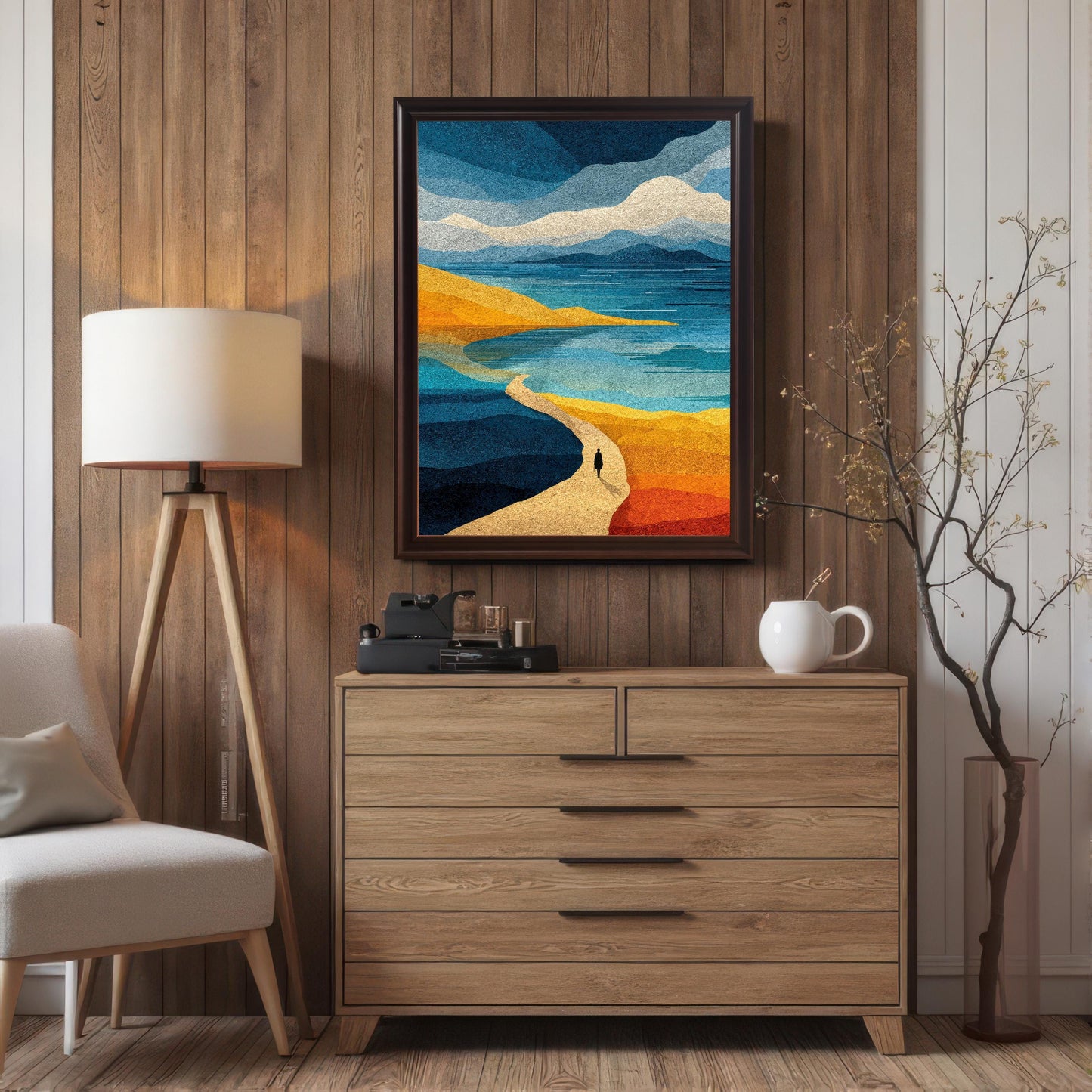 A coffee wood framed abstract landscape wall art piece hanging centered over a mid-century modern wooden dresser in a room with warm vertical wood paneling and a tall tripod floor lamp.