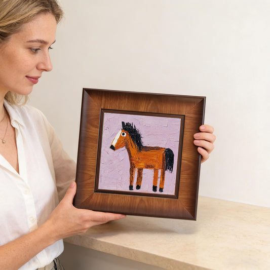 A woman holding the square beveled wood frame, providing a clear sense of scale for the horse painting's size and physical quality.