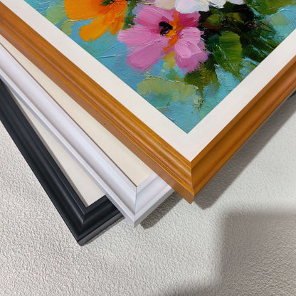  A close-up, top-down view of three picture frames stacked on each other—black, white, and wood-toned—all containing the same floral artwork.