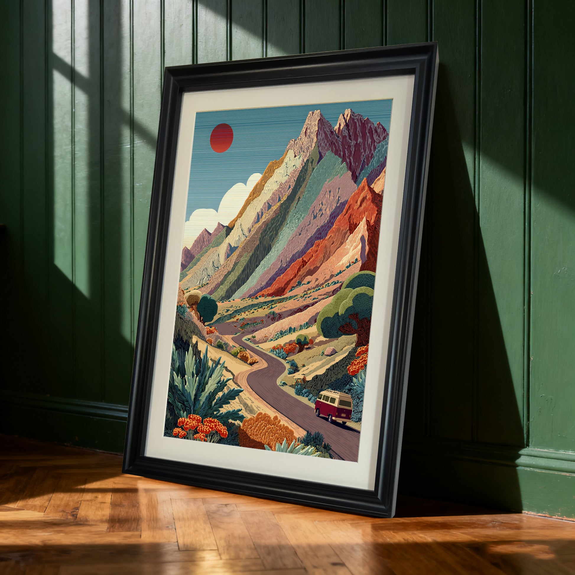Mountain Road Trip,Black-framed art print of the colorful mountain road trip leaning against a dark green paneled wall. Natural light casts shadows on the wooden floor.