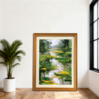 Large abstract lily pond painting with bold green and yellow strokes, framed in light brown wood, placed on a wooden floor next to a white potted palm plant in a minimalist white room with a large black-framed window.
