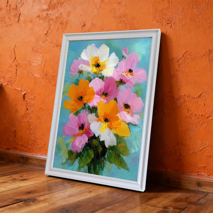 A vertical oil painting of vibrant pink, orange, and white flowers in a white frame, leaning against a textured, bright orange wall on a wooden floor.
