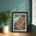 Large, black-framed art print of the colorful mountain road trip scene resting on the floor next to a potted palm, against a teal green paneled wall.