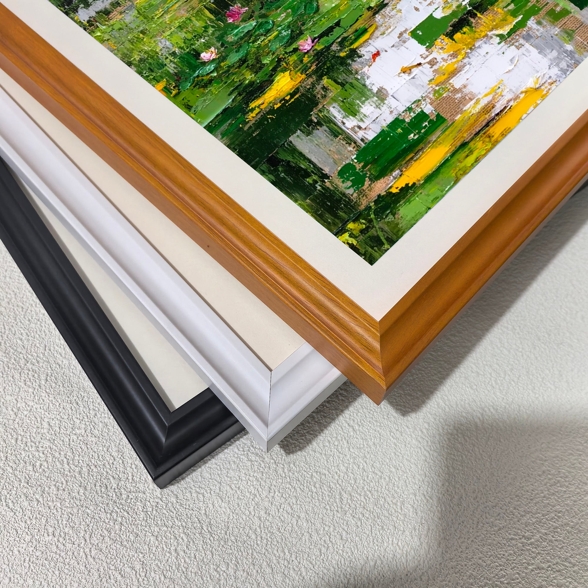 Close-up corner detail of the art print showing three stacked frame options: , white, orange, and black.