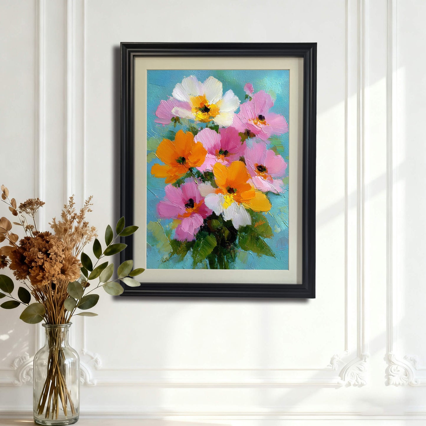 The floral painting in a black frame with a white mat, hanging on a white wall with elegant decorative molding, positioned behind a glass vase of dried flowers.