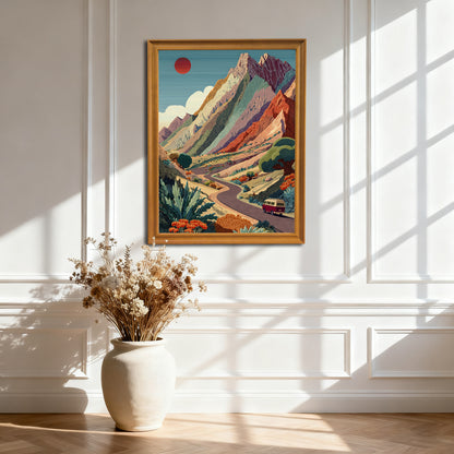Natural wood-framed art print of the colorful mountain road trip scene, hanging on a white paneled wall. Sunlight casts dramatic geometric shadows.