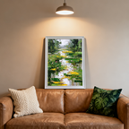 Abstract lily pond painting in a white frame, leaning against a neutral beige wall above a brown leather sofa, with decorative pillows and a pendant light overhead casting a spotlight on the art.