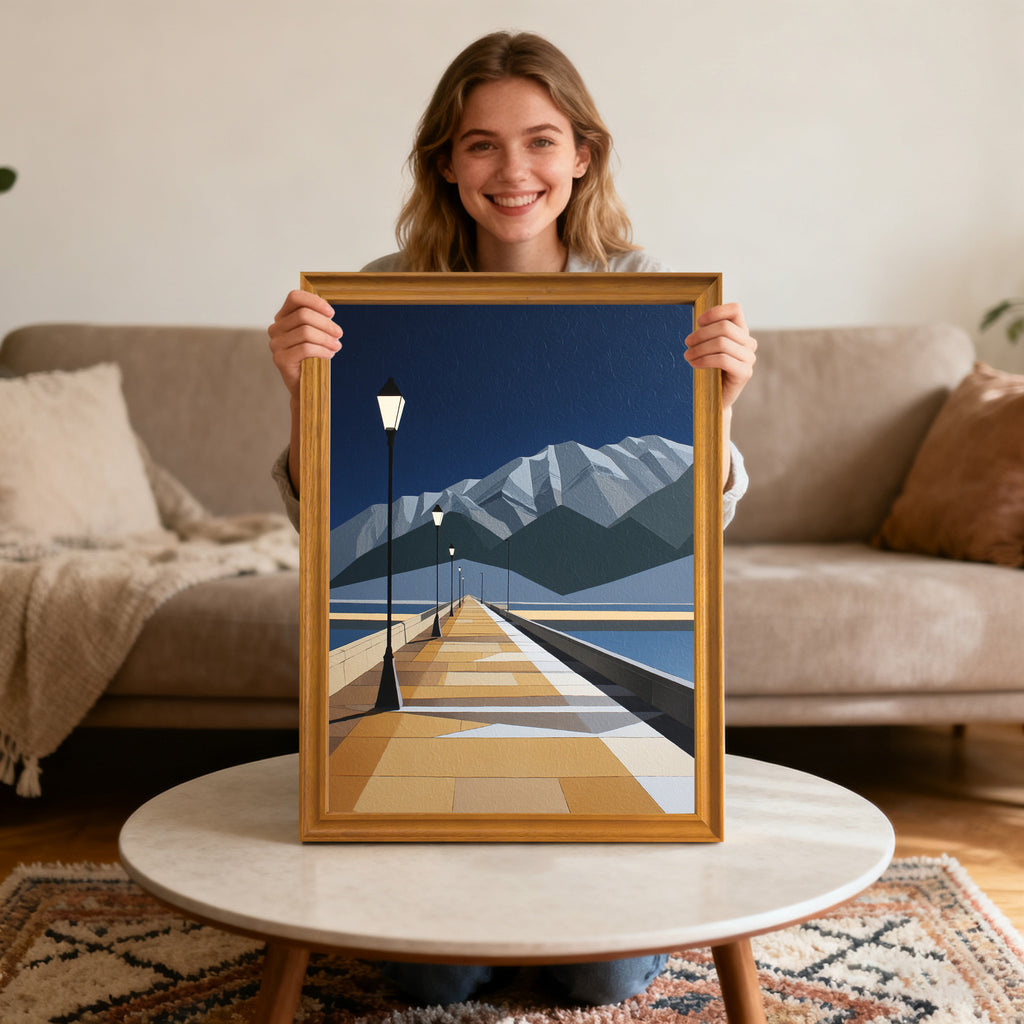 Smiling young woman holding up the geometric pier and mountain art print in a gold-colored wood frame, sitting by a marble coffee table in a living room.