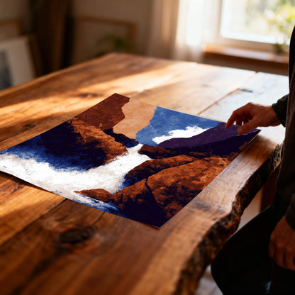Unframed abstract waterfall art print with strong blue and orange colors, lying on a rustic, live-edge wooden table in soft sunlight.