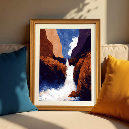 Framed abstract waterfall art print in a light wood (natural) frame, resting on a beige sofa between a blue and a yellow pillow.