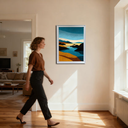 Full-body shot of a woman in a brown shirt and black pants walking past a vertical abstract stippled landscape art print in a thin white frame, hanging on a cream wall in a brightly lit hallway.
