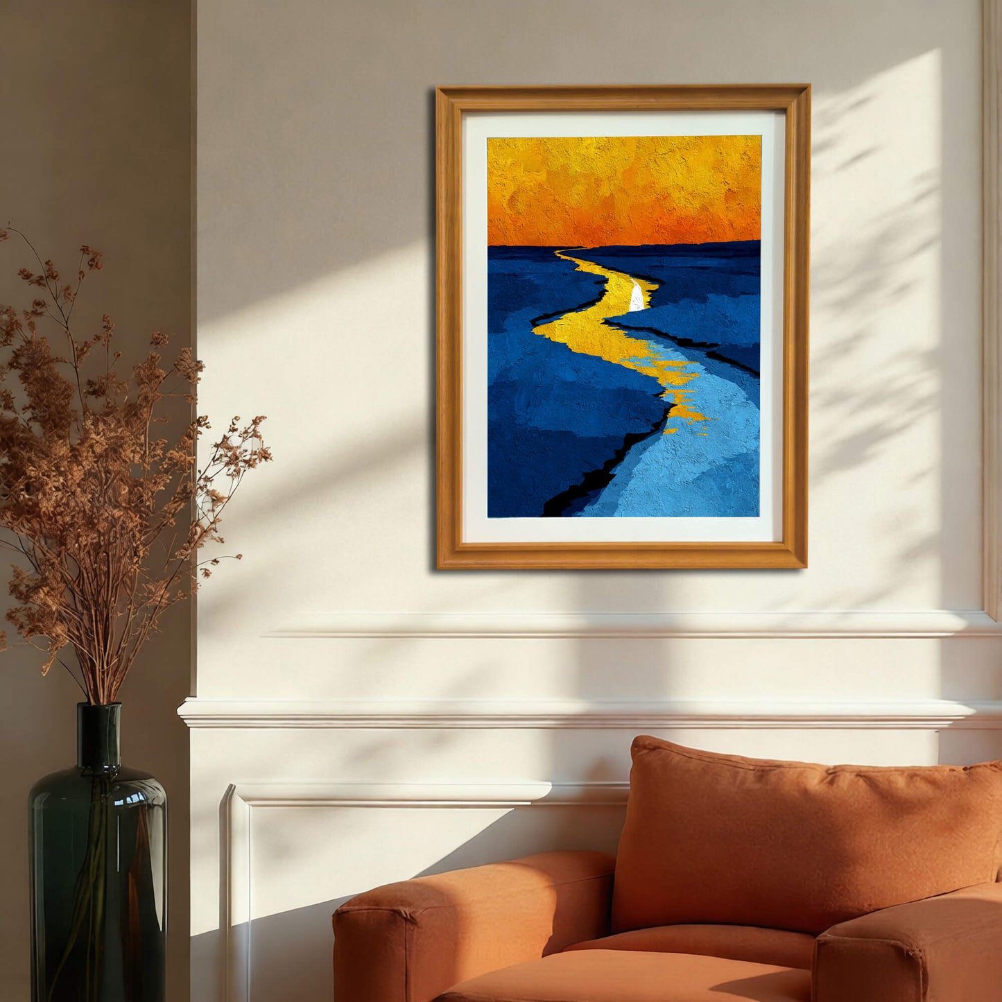 Abstract print of a winding yellow line through blue water, framed in light wood (natural), hanging above an orange armchair next to a decorative vase.