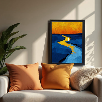 Abstract print of a yellow path or river against blue tones and an orange sky, framed in black, resting on a white sofa next to orange pillows.