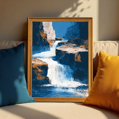 Vertical abstract waterfall art print in a natural light brown wood frame, resting on a neutral-colored couch between a blue and a yellow throw pillow, lit by sun and shadow.
