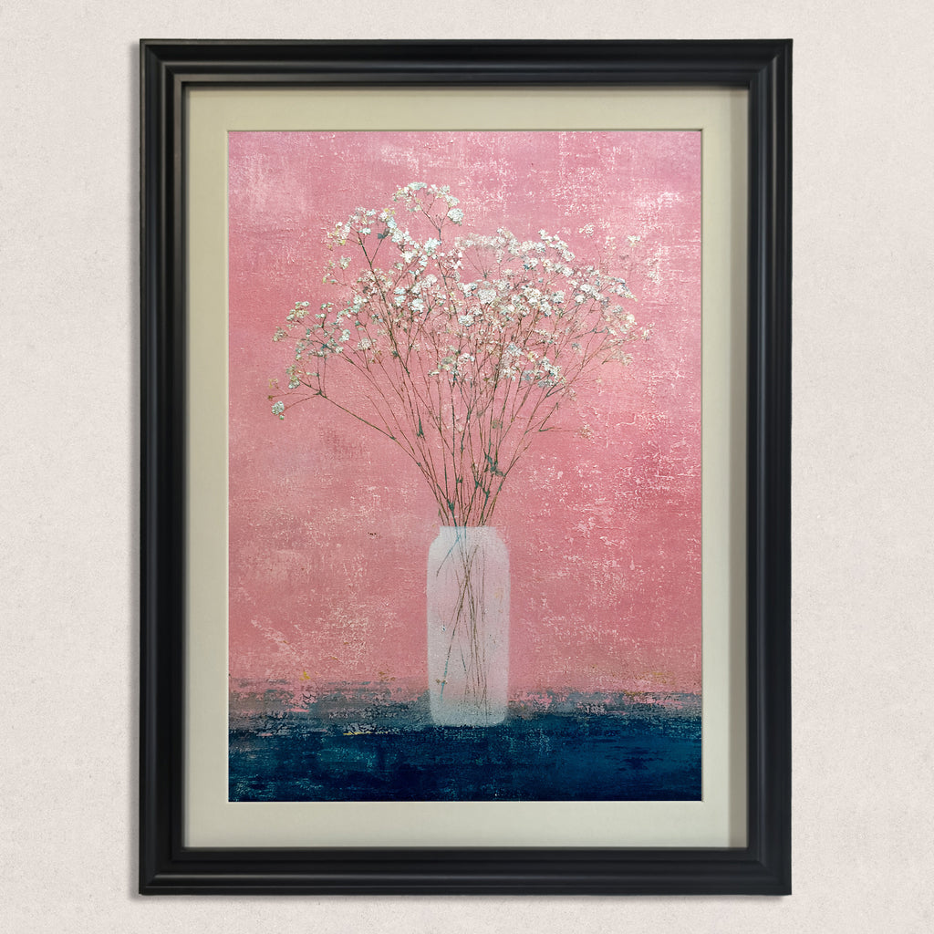 Close-up of the art print: small white flowers (baby's breath) in a tall, slender vase against a textured, vibrant pink wall and a contrasting dark blue surface, framed in black.