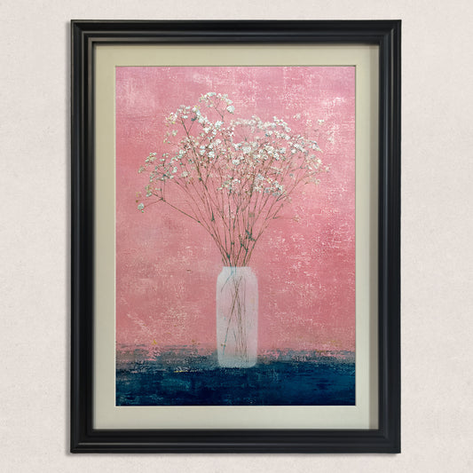 Close-up of the art print: small white flowers (baby's breath) in a tall, slender vase against a textured, vibrant pink wall and a contrasting dark blue surface, framed in black.