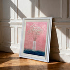 White-framed art print of baby's breath in a vase against a textured pink and dark blue background, leaning on a hardwood floor against a white paneled wall with strong sun shadows.