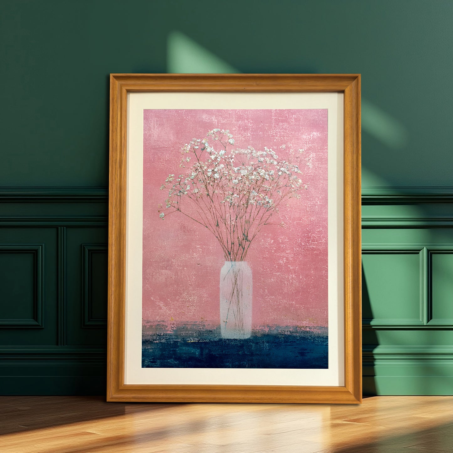 Natural wood-framed art print of baby's breath in a vase against a textured pink and dark blue background, leaning on the floor against a dark emerald green paneled wall.