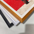 Close-up view of three stacked wood picture frame corners in black, white, and natural brown, showing the art print inside which features striking red and textured white colors.
