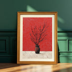 Natural wood-framed art print of a black branching silhouette against a textured red background, leaning on the floor against a dark forest green paneled wall.