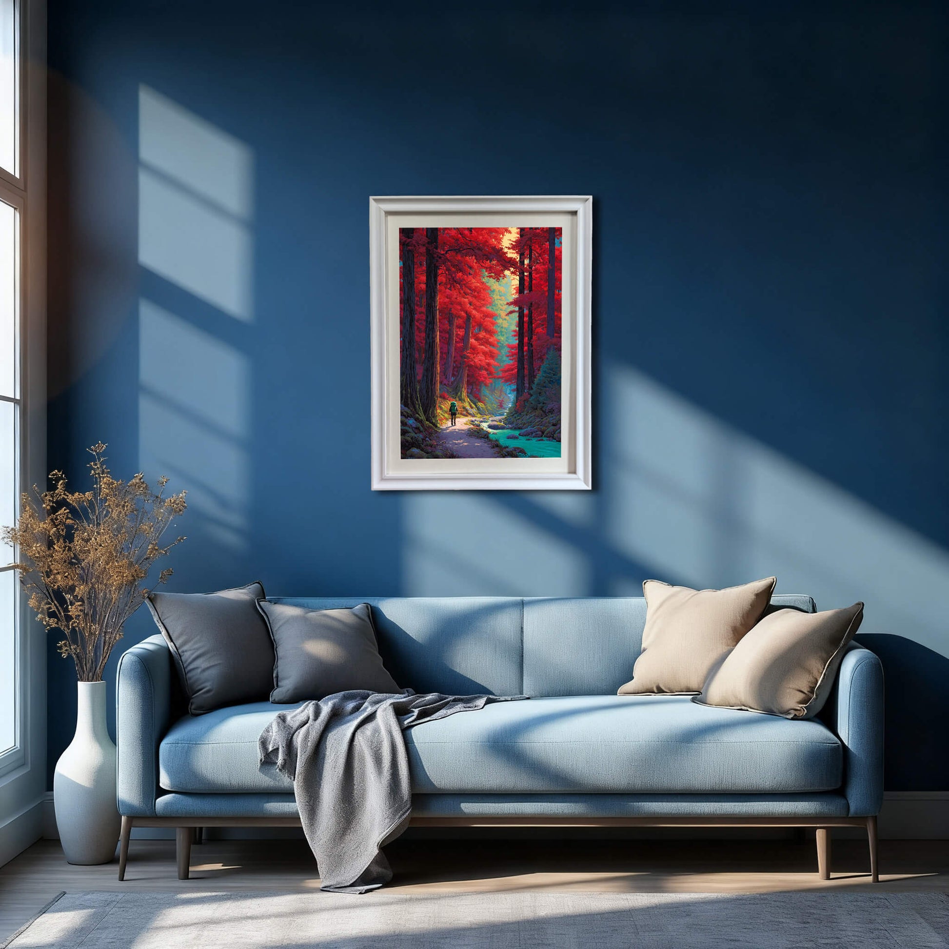 A white framed landscape artwork centered on a dark blue accent wall above a modern light blue sofa with grey pillows.