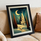 Whimsical art print of a house under a crescent moon on a snowy path, framed in black, angled while resting on a tan fabric sofa with a rust-colored pillow.