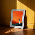 Minimalist lighthouse print in a white frame, leaning on a wooden floor against a bright yellow beadboard wall, in dramatic sunlight.