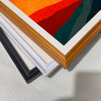 Close-up corner detail of the minimalist lighthouse artwork showing three stacked frame options:  white, orange, and black."