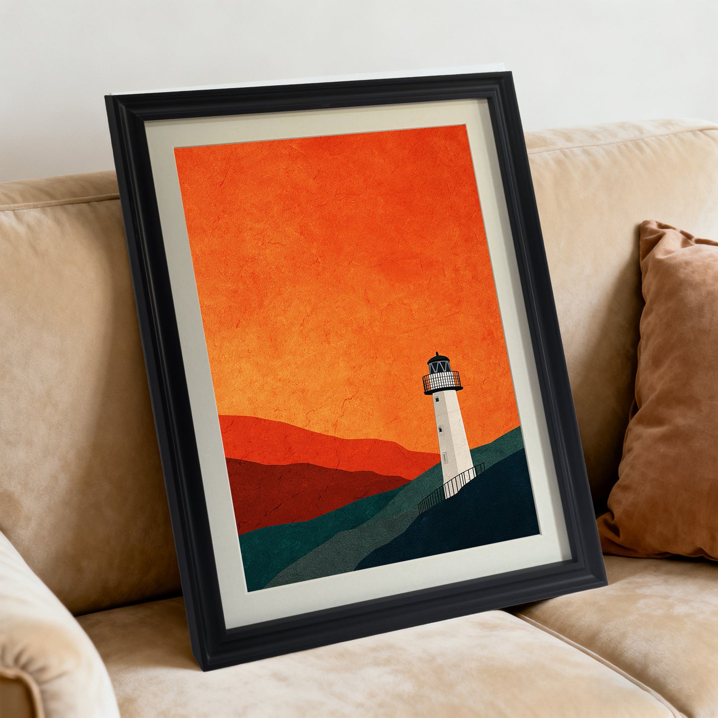 Minimalist lighthouse art print featuring a textured orange sky, framed in black with a mat, angled while resting on a tan fabric sofa with a rust-colored pillow.