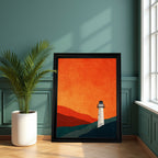 Minimalist art print of a white lighthouse on a dark blue hill beneath an intense orange sky and red mountains, in a thick black frame, leaning on a wood floor against a dark teal paneled wall next to a large potted plant.