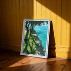 A white-framed art print leaning on a wooden floor against a bright yellow, paneled wall. Dramatic sunlight creates sharp shadows and highlights on the wall and floor.