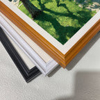 A stack of four frame corners: black, off-white, white, and a light wood grain (brown). This displays the different framing options available for the art print.