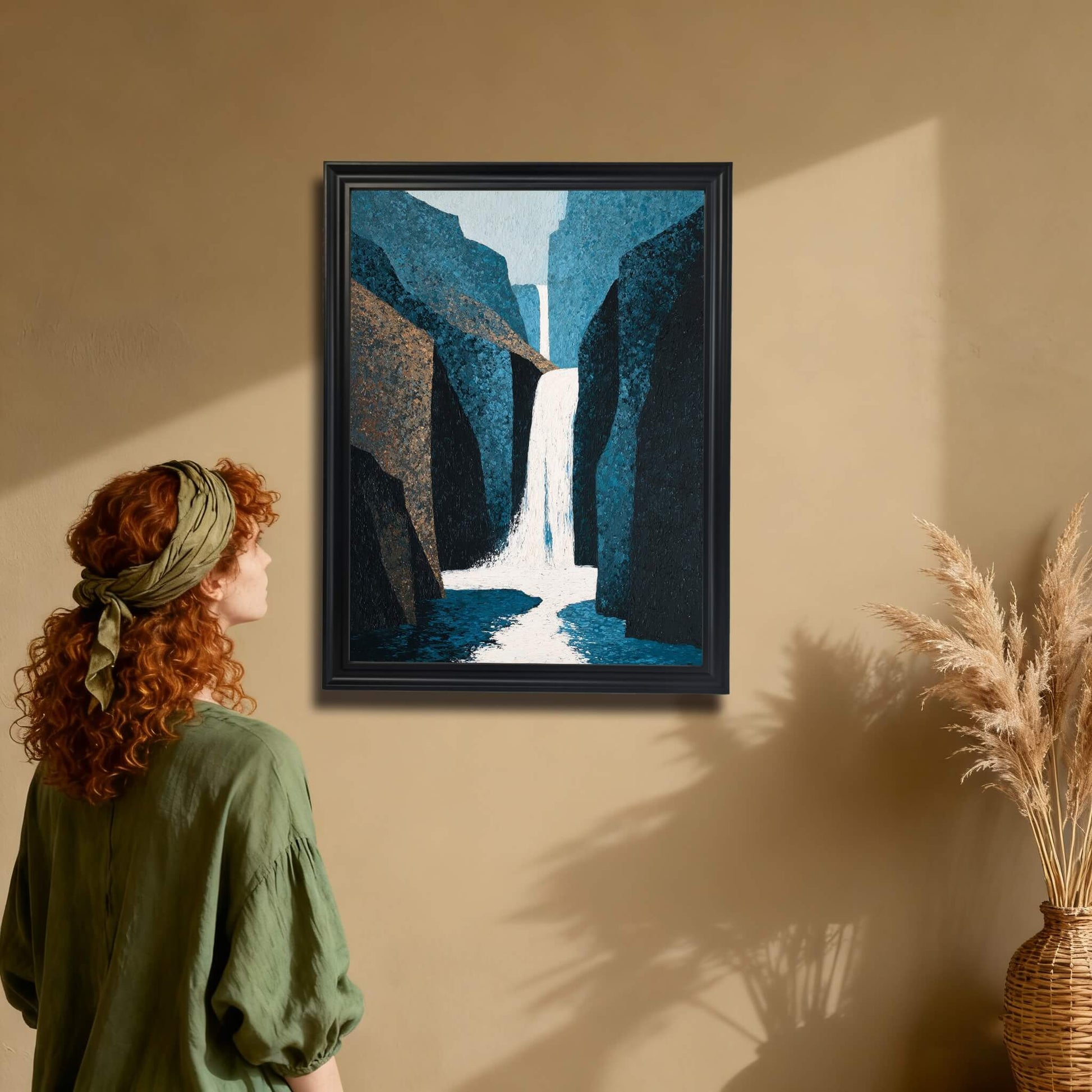 Abstract waterfall art print in a black wood frame hanging on a tan wall. A woman in a green shirt is admiring the framed canyon and waterfall painting, showing the scale and decor style.