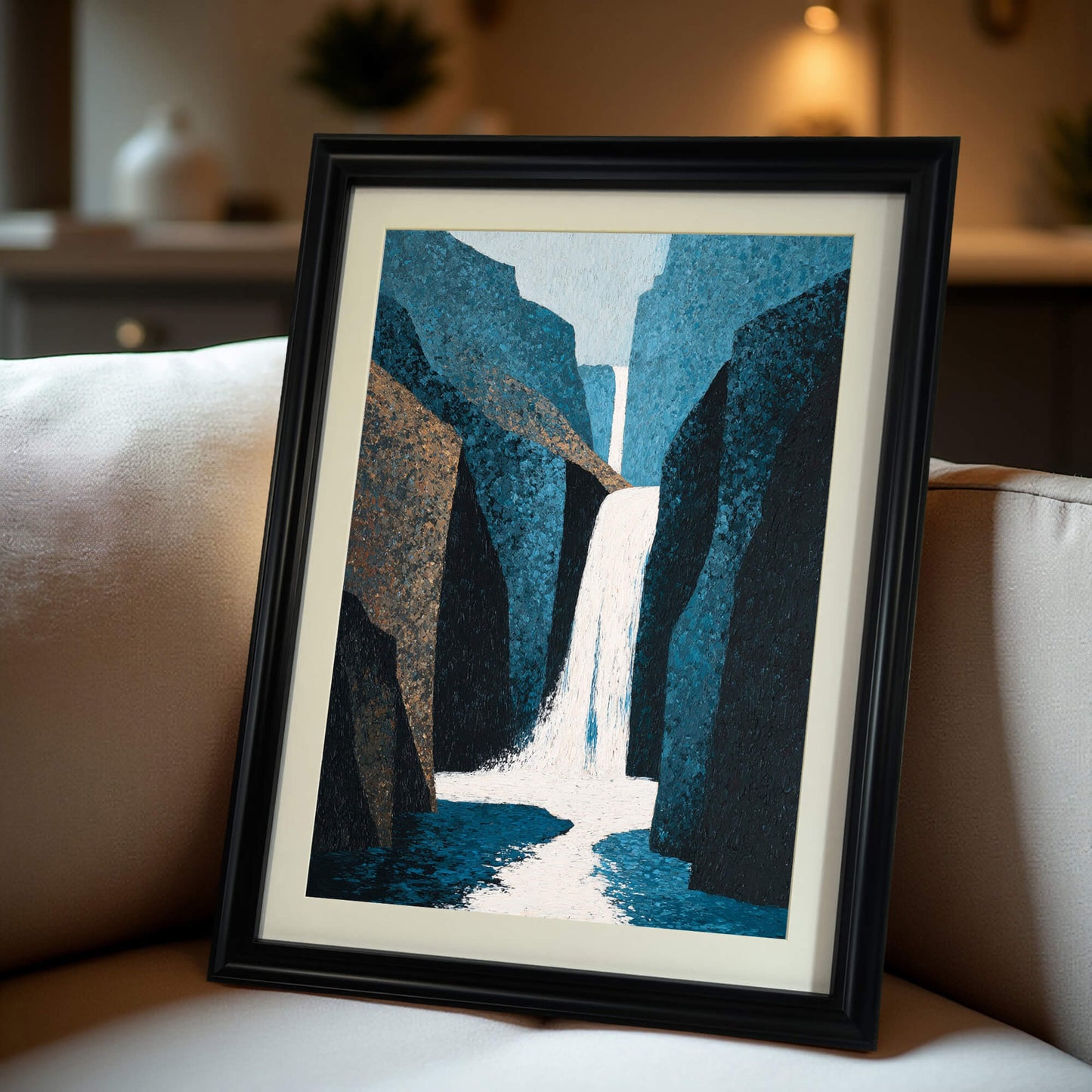 Abstract waterfall art print in a black wood frame with a mat, propped up on a cream-colored couch, offering a close-up view of the framed print in a home setting.