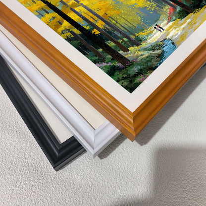 A close-up, angled shot of three stacked picture frames (black, white, and wood) showing the corner detail of the forest artwork.