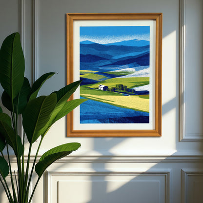 Vertical abstract farm landscape print in a natural brown wood frame, hanging on a gray paneled wall next to a large green houseplant in a sunlit room.