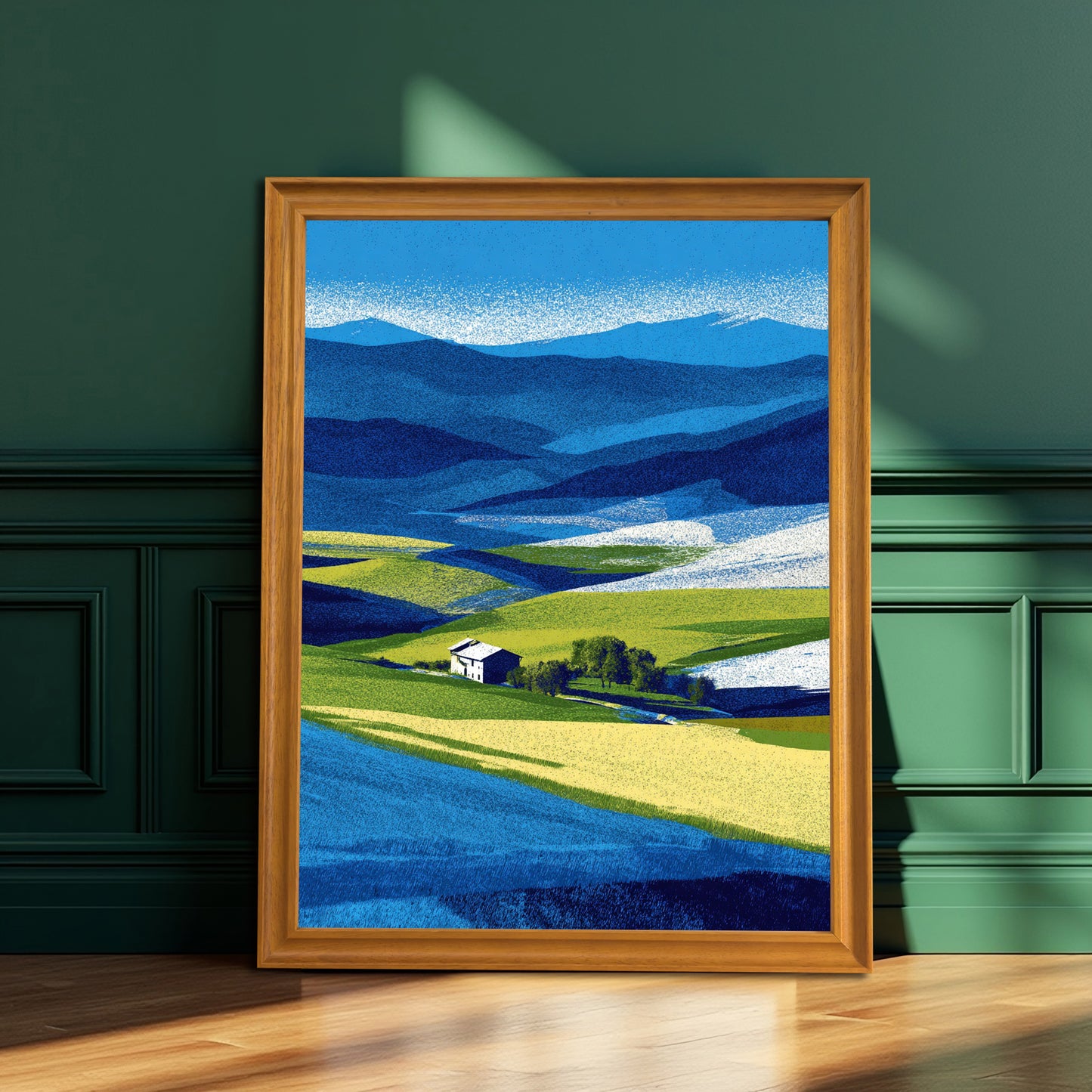 Vertical abstract farm landscape print in a warm natural brown wood frame, resting on a wooden floor against a dark emerald green paneled wall.