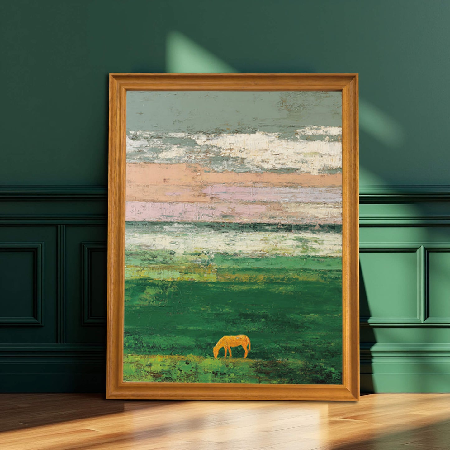 A framed art print of an abstract green landscape with a golden horse silhouette, resting on a wooden floor against a dark, paneled green wall. The frame is natural wood/light brown.