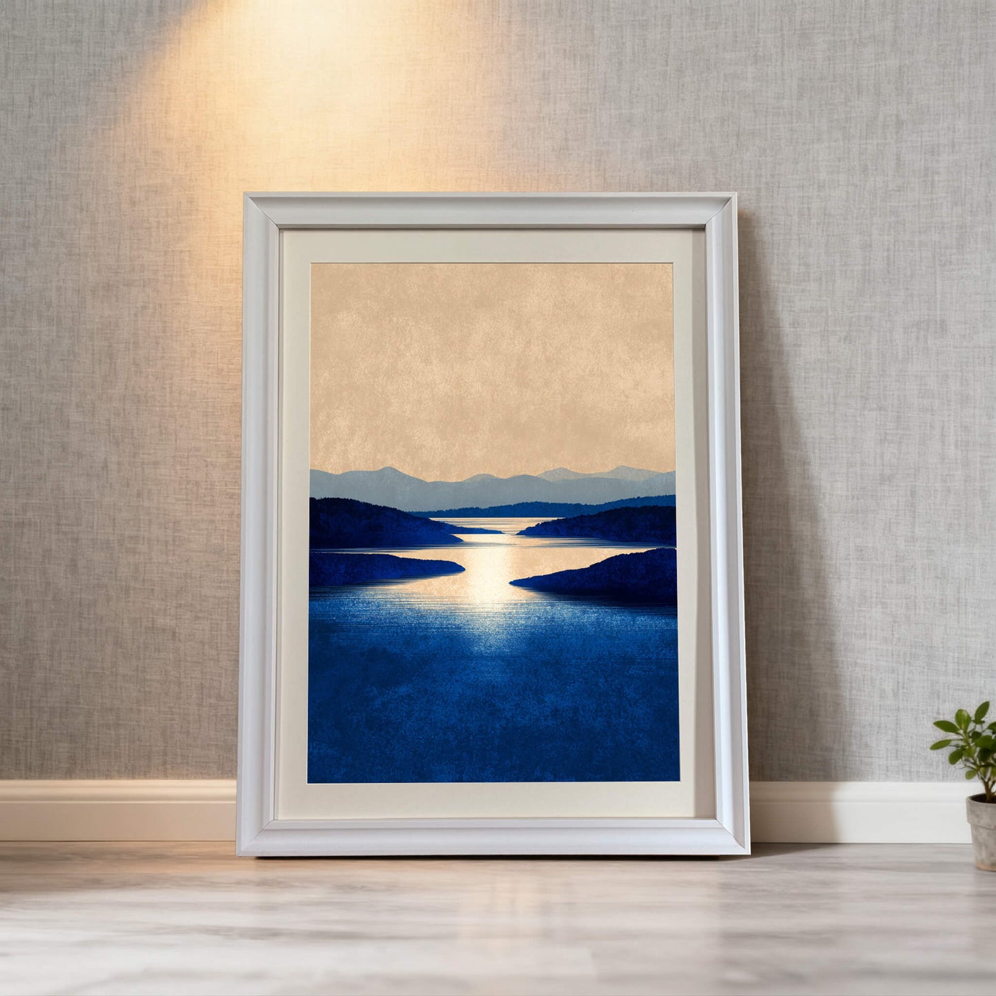 Framed art print of a minimalist blue landscape in a white frame, leaning on a light wood floor against a textured gray wall.