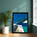 Large, black-framed abstract landscape art print resting on the floor next to a potted palm plant, against a teal green paneled wall near a bright window.