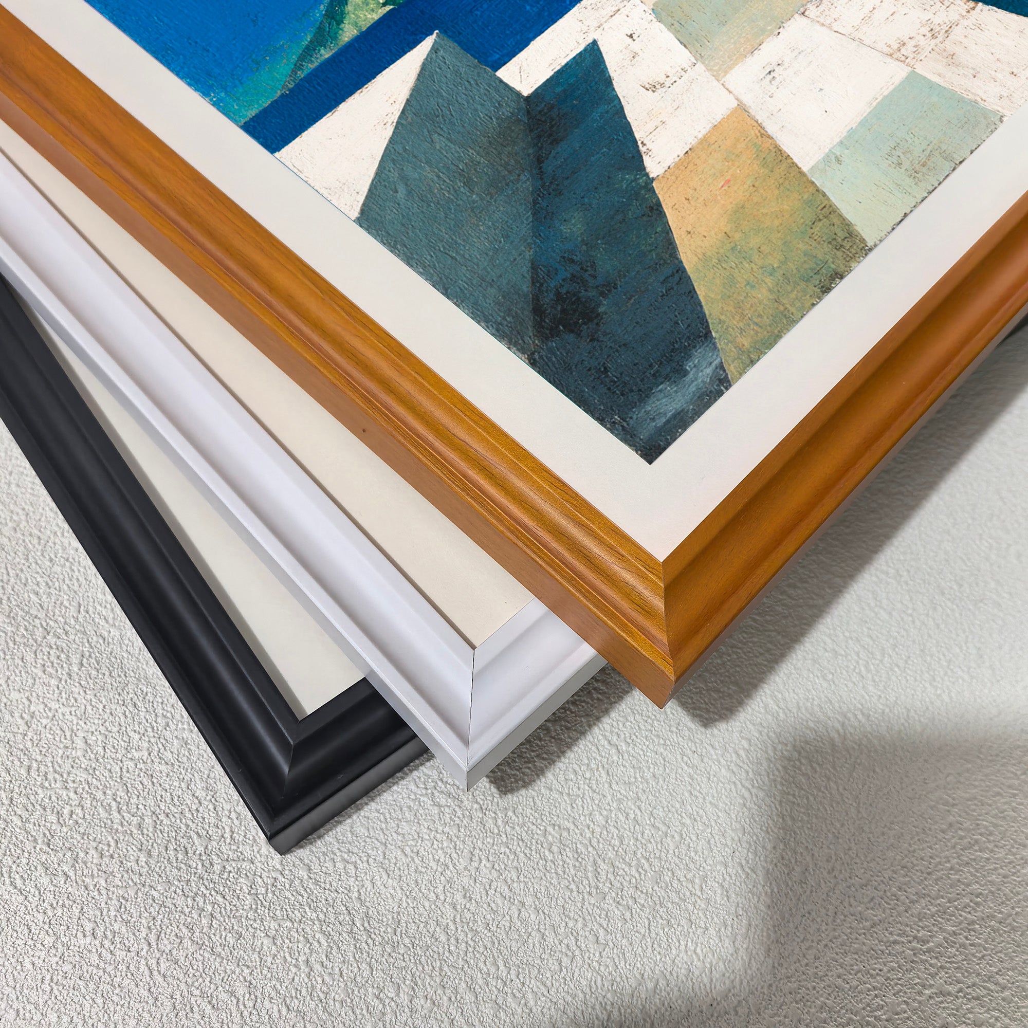 Close-up corner detail of the art print showing three stacked frame options: , white, orange, and black.